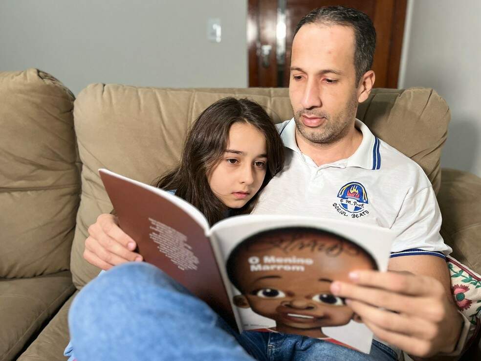 Historiador César Willer de Sousa e a filha lendo "O Menino Marrom", de Ziraldo  — Foto: Ernane Fiuza/TV Globo